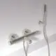 Thermostatarmatur in Silber für Bad mit zwei runden Griffen, montiert an der Wand, hergestellt von Ideal Standard. Handbrause mit flexibler Schlauchverbindung.